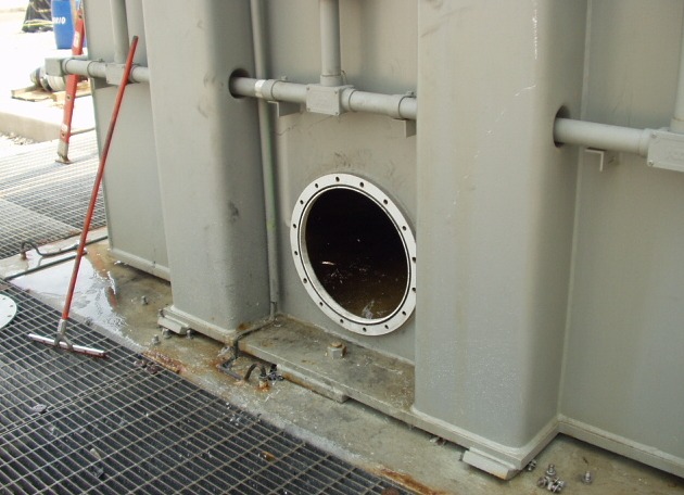 The split transformer tank with its inspection hatch open, standing water visible inside.